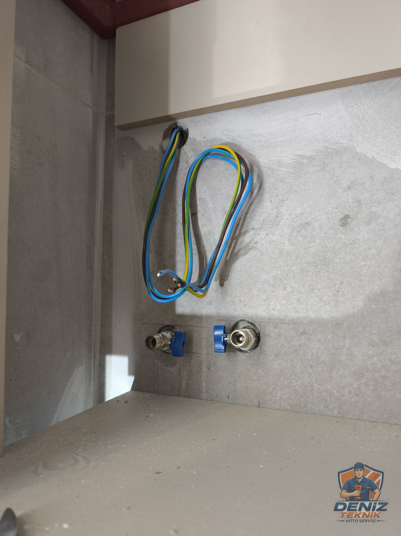 Dolap içinde vanalı iki su ucu ve elektrik kablosu — ani su ısıtıcı montajı öncesi